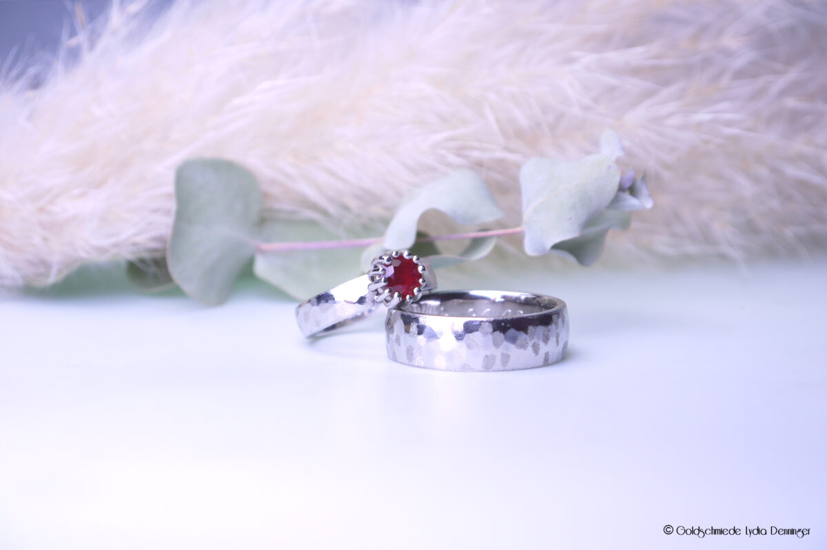 Handgefertigte Trauringe aus Platin mit funkelndem Rubin – Symbol für Liebe und Beständigkeit.